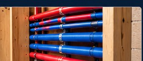 Red and blue PEX pipes inside an open wall.